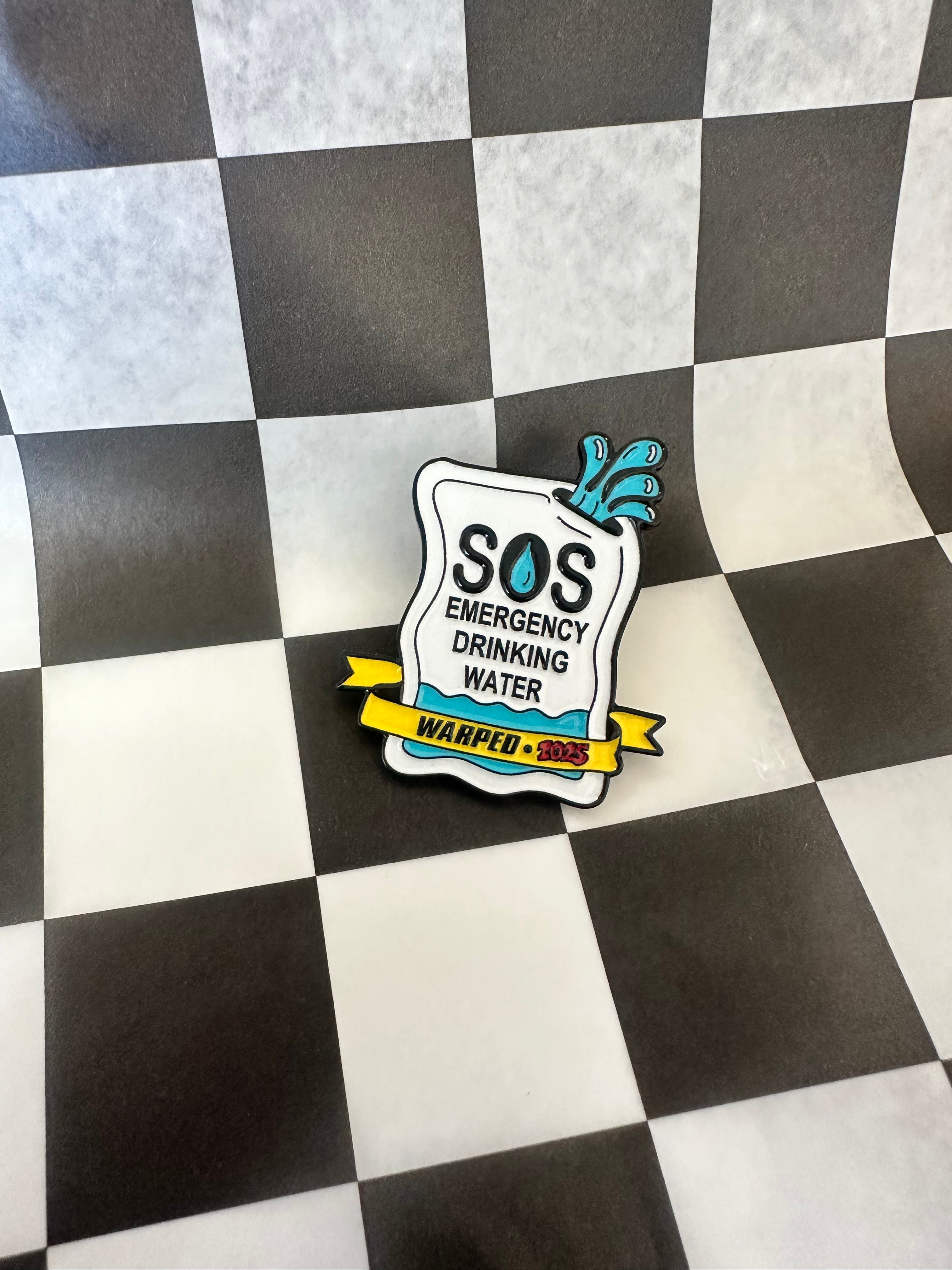 Pin with 'SOS Emergency Drinking Water' design on a checkered background