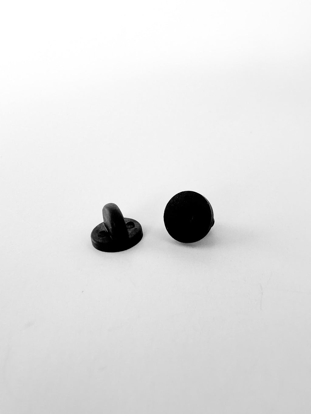 A pair of black PVC rubber pin backs