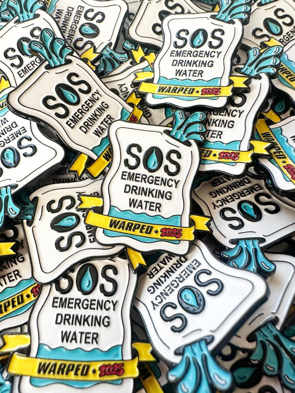 Stack of SOS Emergency Drinking Water enamel pins