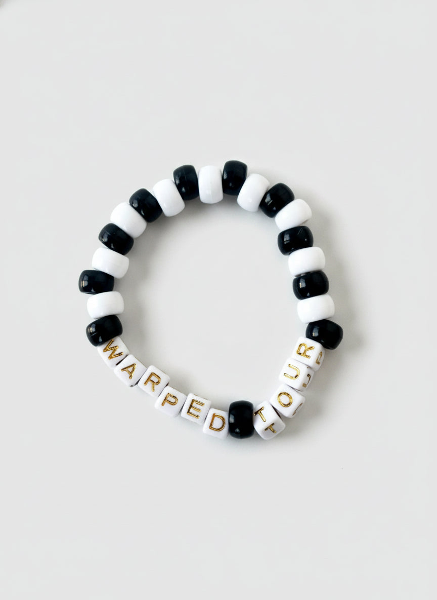 Black and white beaded bracelet with "Warped Tour" text on a white background