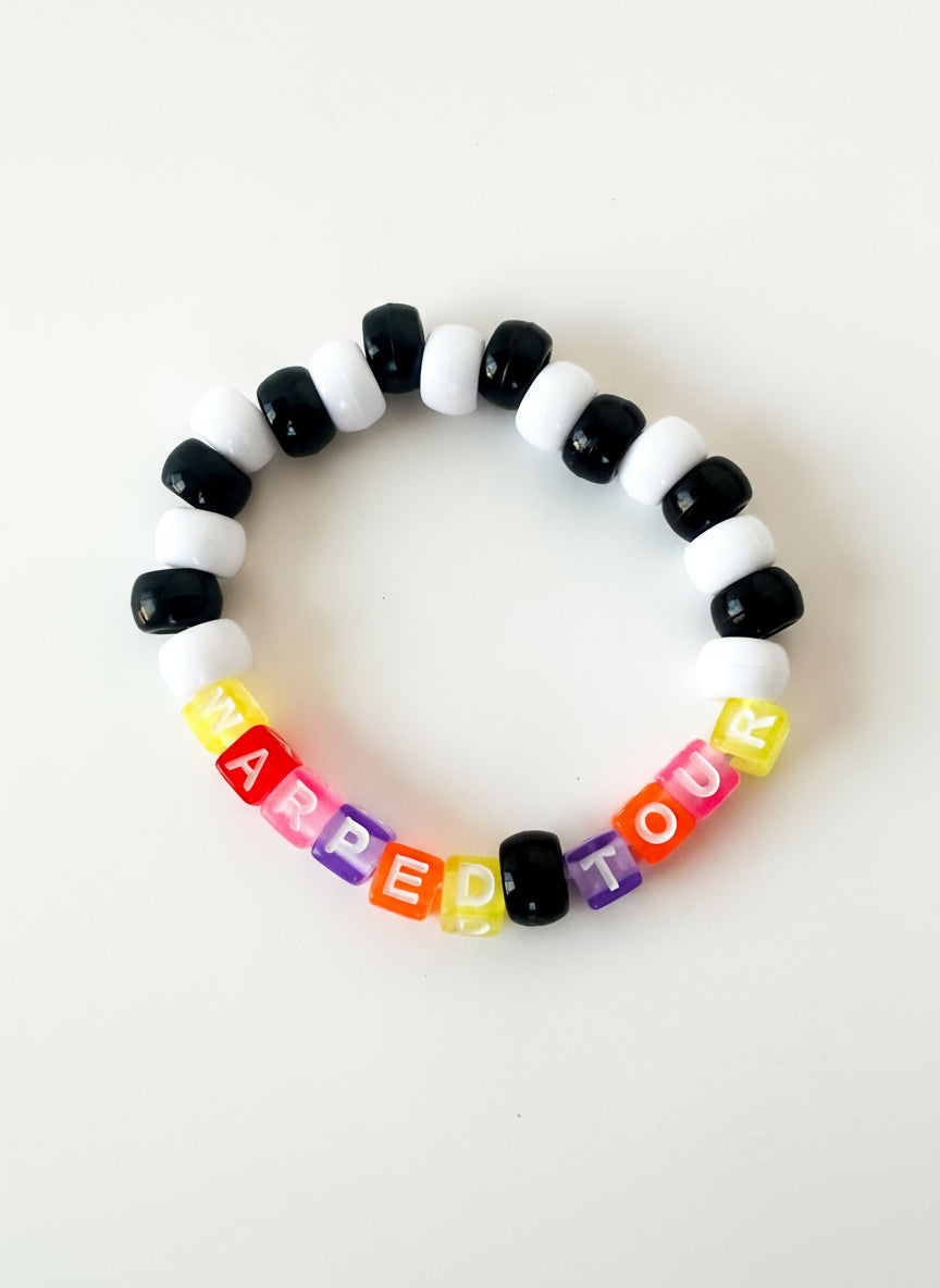 Colorful beaded bracelet with letter beads spelling out "Warped Tour" on a white background